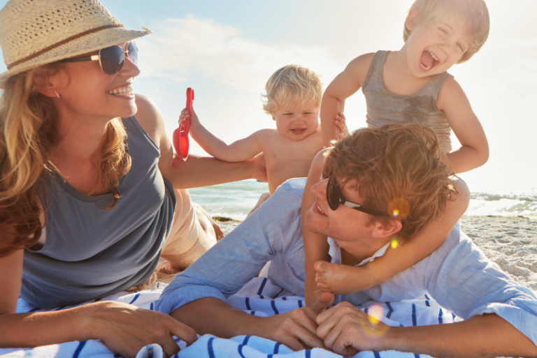 Family of four on the beach, enjoying the sunshine.